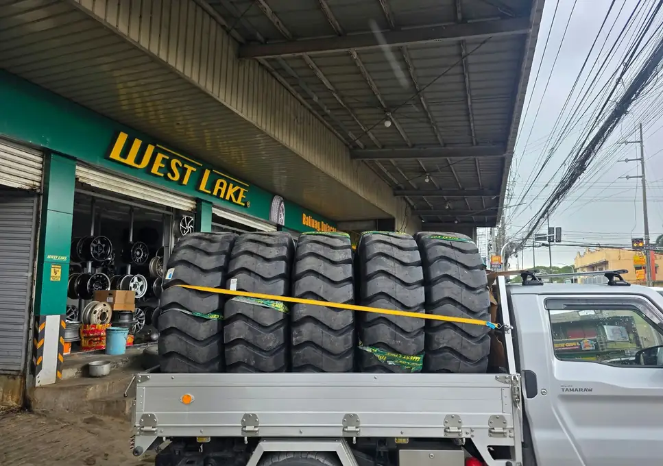 Heavy-equipment tires strapped on a pickup bed outside the shop