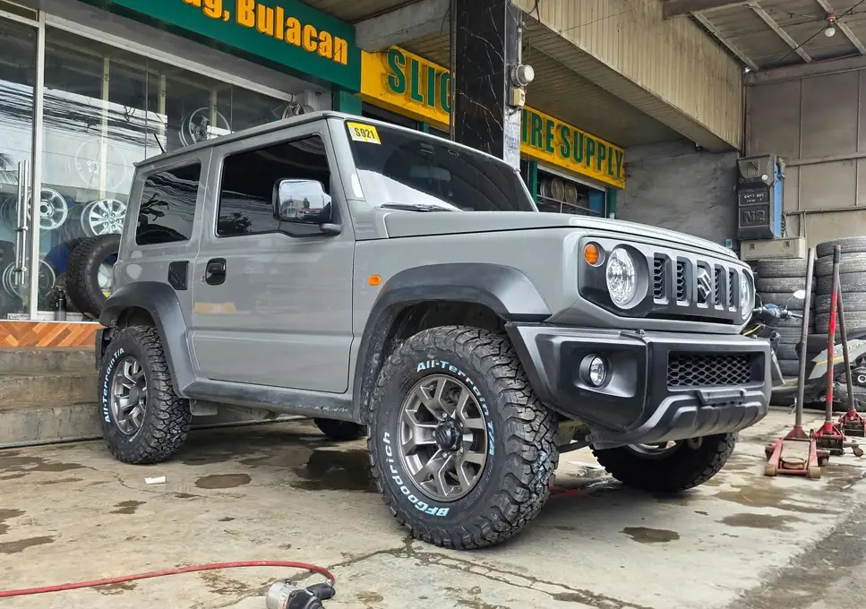 A grey Suzuki Jimny on all-terrain tires at the shop