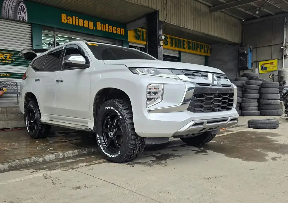 A white Mitsubishi Montero Sport on black mags and all-terrain tires